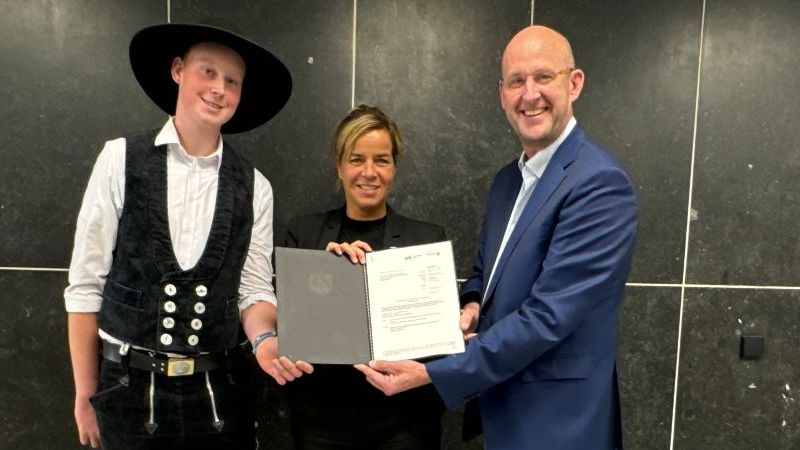 Das Bild zeigt NRW-Wirtschaftsministerin Mona Neubauer, wie sie zusammen mit zwei Personen der Ing.-Holzbau-Rohde GmbH einen Förderbescheid überreicht.