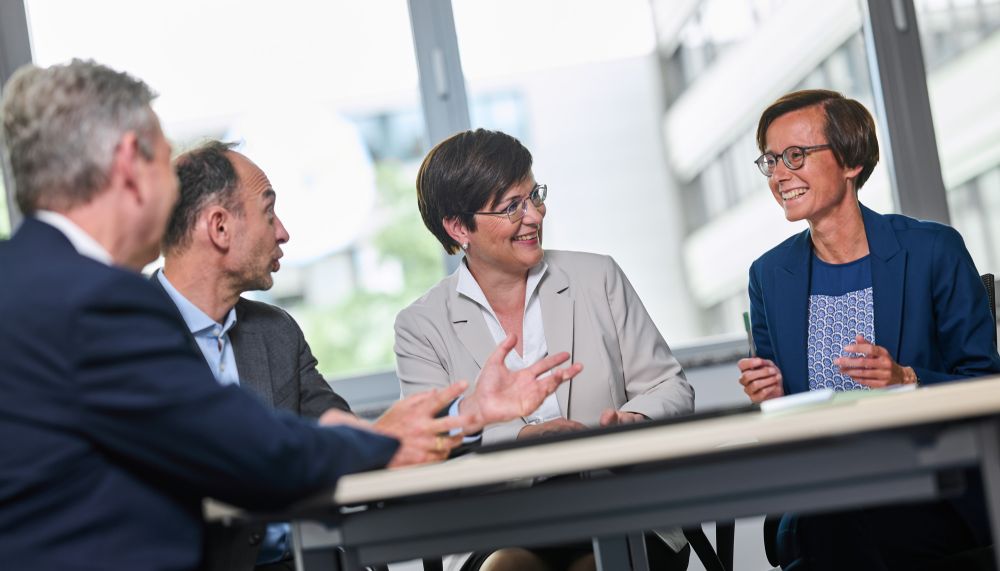 The management of PtJ sits at a table and talks to each other.